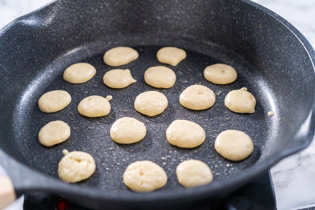 Fritar mini panqueca de cereal em uma frigideira antiaderente.