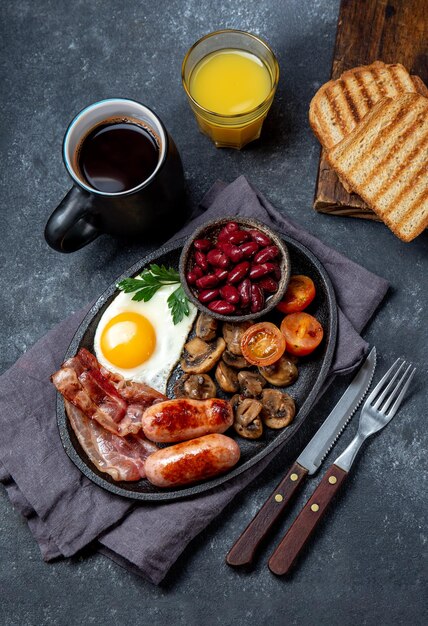 Foto frite o café da manhã inglês completo com ovos fritos, salsichas, bacon, morcela, feijão, torradas e café da