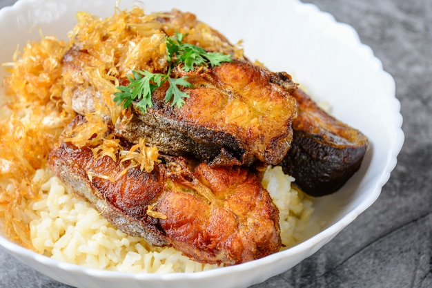 Frito em fatias de peixe Pangasius com alho, servido com arroz integral.