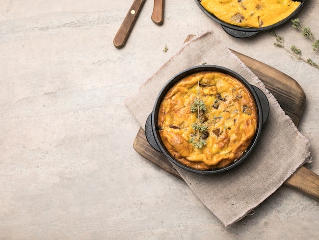 Frittata con champiñones en una sartén sobre fondo de madera. Fritata es un plato de desayuno italiano.