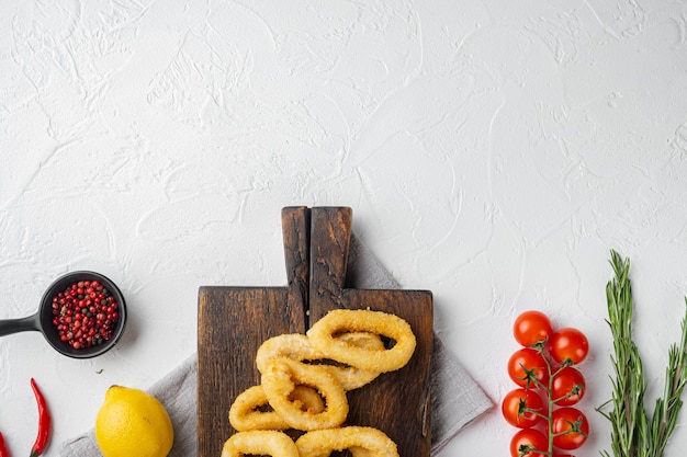 Frittierte Calamari oder Zwiebelringe, auf Servierbrett, auf weißem Steintischhintergrund, Draufsicht flach, mit Kopienraum für Text