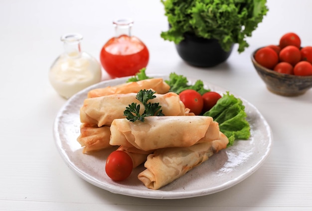 Frittierte Frühlingsrollen, beliebt als Lumpia oder Popia. Serviert auf weißem Teller, weißer Tisch mit würziger Sauce und Mayonaise. Platz für Text kopieren