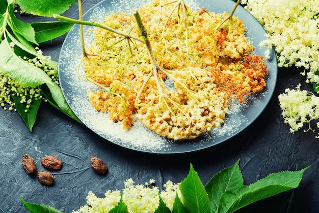 Frittierte holunderblüten im teig mit puderzucker. frühlingsblumendessert