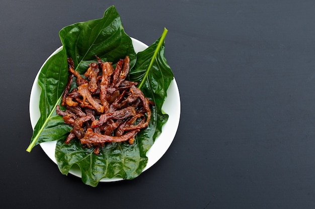 Frittiertes sonnengetrocknetes Schweinefleisch auf dunklem Hintergrund. Draufsicht