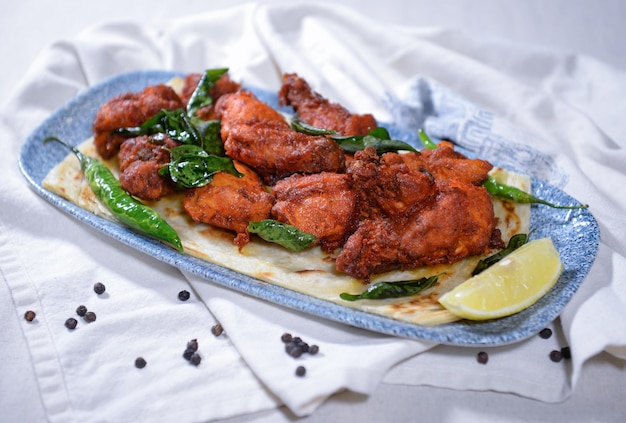 Fritura de pollo Alosra servida en un plato aislado en una vista lateral de fondo oscuro