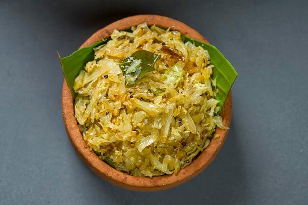 Fritura de repollo o plato salteado para las comidas de kerala, que es una comida vegetariana muy sabrosa dispuesta en una loza de barro que se coloca sobre un fondo de textura gris