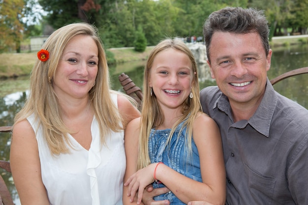 Fröhlich lächelnde dreiköpfige Familie zusammen auf der grünen Wiese am Sommertag