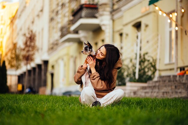 Fröhlich lächelnde Frau in Freizeitkleidung fühlt sich glücklich, wenn sie ihren entzückenden Hund York Terrier hält