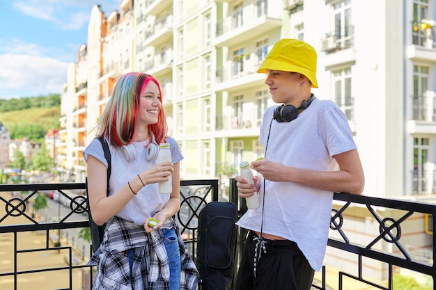 Fröhlich sprechende Studenten Teenager Kerl und Mädchen in der Stadt trinken Milchjoghurt aus der Flasche. Lifestyle, Ernährung, Jugendgesundheit