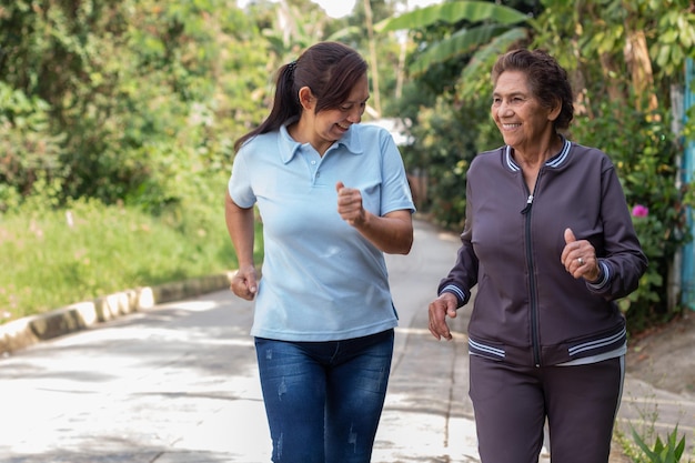 Fröhliche ältere Mutter und Tochter joggen im Freien in einer Morgenübung Gesundes Wohnkonzept