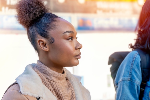 Fröhliche Afrikanerin hält eine Tasse Kaffee und wartet auf eine Straßenbahn