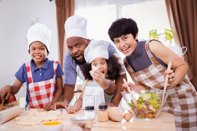 Fröhliche afroamerikanische Familie genießt gemeinsam, während sie das Mehl für die Herstellung von Keksen zu Hause zubereitet. Konzept der afroamerikanischen Familie