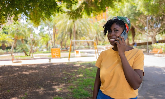 Fröhliche afroamerikanische junge Frau, die mit dem Handy spricht