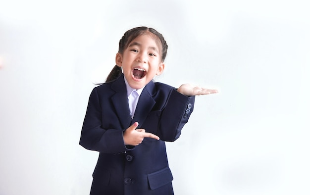 Fröhliche asiatische Kinder, die einen Schulanzug tragen, der die offene Hand als Willkommen isoliert zeigt