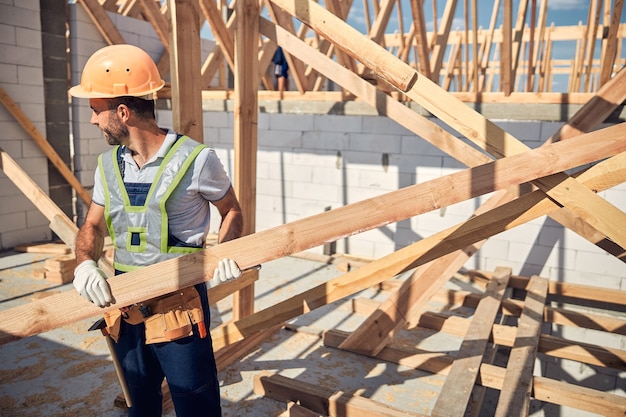 Fröhliche bärtige männliche Person, die den Kopf dreht, während sie seinen Vorarbeiter auf der Baustelle beiseite sieht