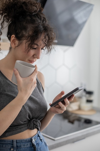 Fröhliche brünette Frau, die im Internet surft, nutzt Smartphone und genießt eine Kaffeepause im Café?