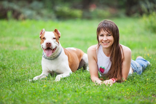 Fröhliche Dame, die auf Gras mit Hund liegt