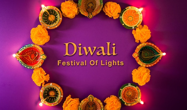 Fröhliche Diwali-Clay-Diya-Lampen, die während der Dipavali-Hindu-Festival of Lights-Feier beleuchtet werden Bunte traditionelle Öllampe Diya auf violettem Hintergrund