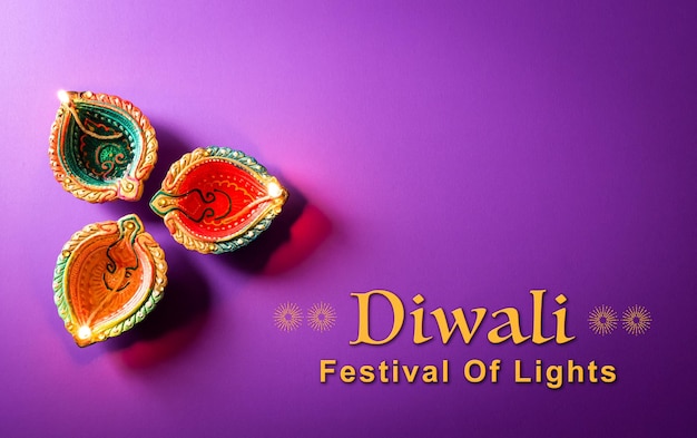 Fröhliche Diwali-Clay-Diya-Lampen, die während der Dipavali-Hindu-Festival of Lights-Feier beleuchtet werden Bunte traditionelle Öllampe Diya auf violettem Hintergrund