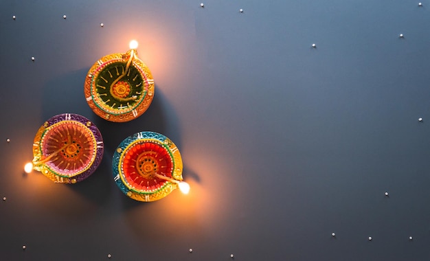 Fröhliche Diwali-Clay-Diya-Lampen, die während der Diwali-Hindu-Festival of Lights-Feier beleuchtet werden Bunte traditionelle Öllampe Diya auf blauem Hintergrund