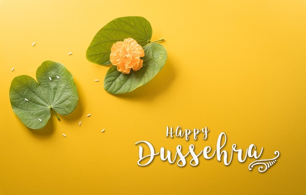 Fröhliche Dussehra-gelbe Blumen, grüner Blattreis und der Text auf gelbem Papierhintergrund Dussehra Indian Festival-Konzept