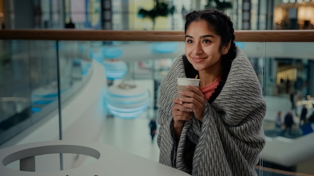 Fröhliche, erholsame arabische, hispanische, ethnische junge Teenagerin, die im Café-Restaurant sitzt