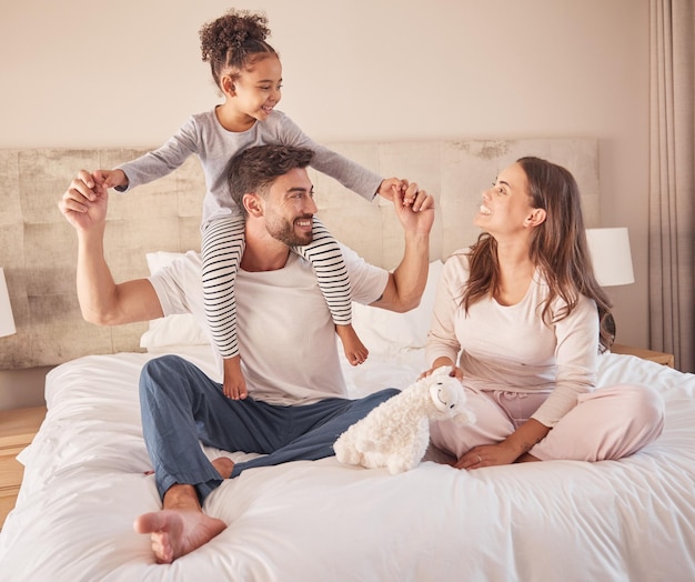 Fröhliche Familie beim gemeinsamen Spielen und Spaß im Bett zu Hause am Morgen Mutter, Vater und Mädchen oder Tochter lachen und spielerischer Spaß mit Liebe im Schlafzimmer zu Hause, während sie sich verbinden