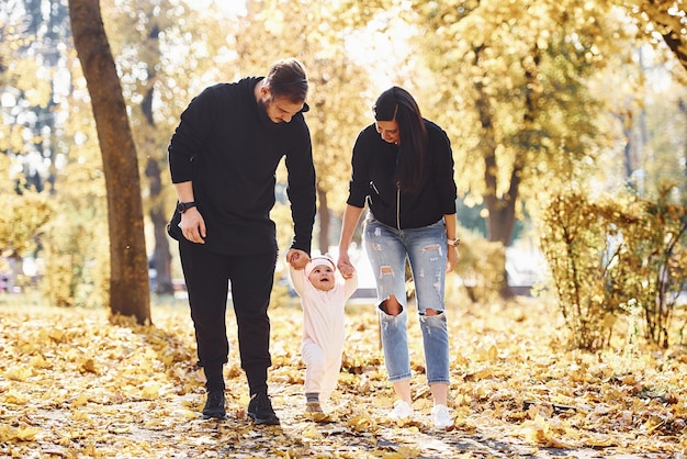 Fröhliche Familie, die zusammen mit ihrem Kind im schönen Herbstpark Spaß hat.