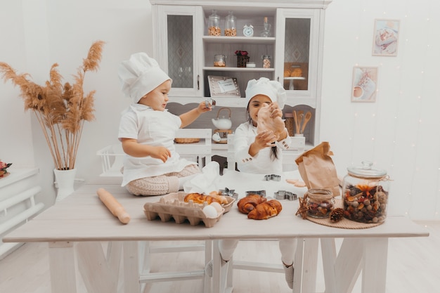 Fröhliche Familie fröhliche Kinder bereiten Teig zu, backen Kekse in der Küche. Kleine Köche.