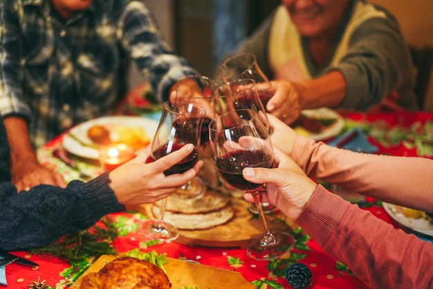 Fröhliche Familie jubelt beim gemeinsamen Weihnachtsessen mit Wein und konzentriert sich auf die rechte Hand