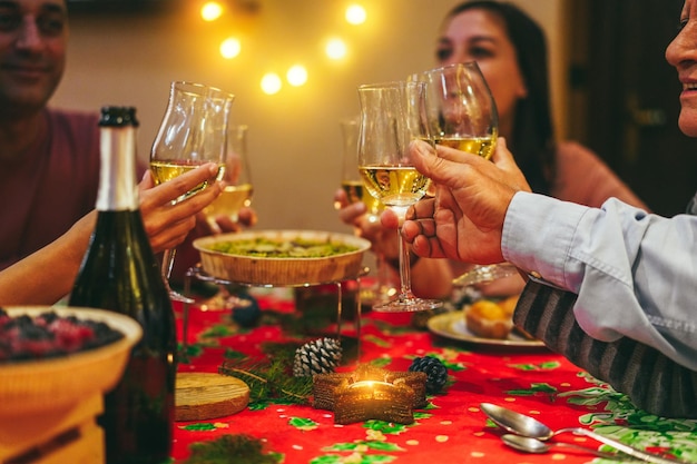 Fröhliche Familie jubelt mit Champagner beim gemeinsamen Weihnachtsessen. Konzentrieren Sie sich auf das rechte Glas