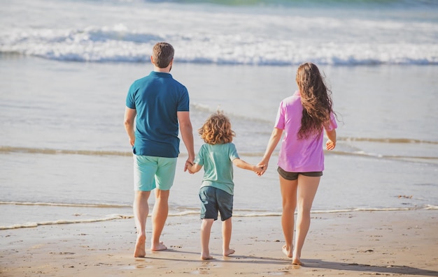 Fröhliche Familienferien, fröhlicher Vater, Mutter, Baby, Sohn, Spaziergang am Meer, Sandstrand, aktive Eltern und Menschen