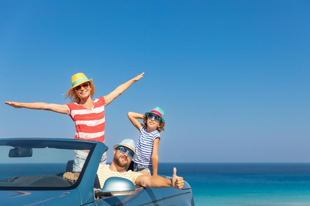 Fröhliche Familienreise mit dem Auto am Meer Mutter, Vater und Tochter, die sich im blauen Cabriolet amüsieren Sommerurlaubskonzept