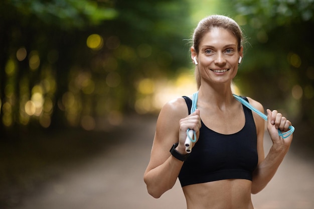 Fröhliche Frau beim Training im Freien mit Springseil