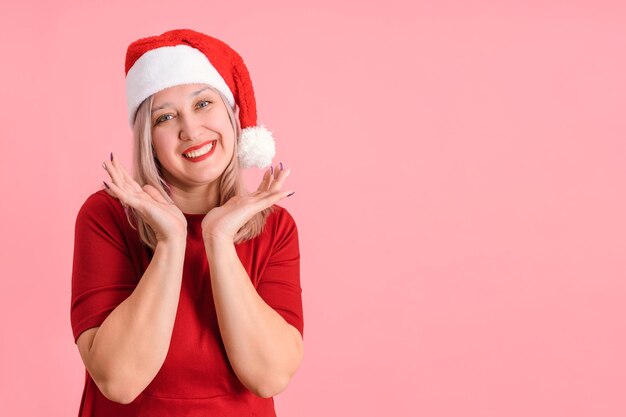 Fröhliche Frau der 40er Jahre in Weihnachtsmütze auf rosa Hintergrund, Exemplar