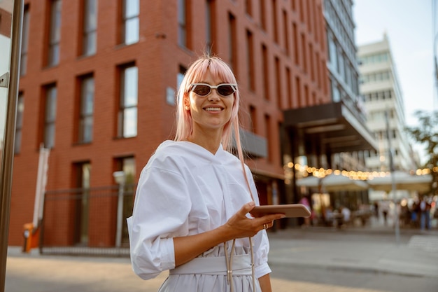 Fröhliche frau, die auf der straße steht und smartphone hält