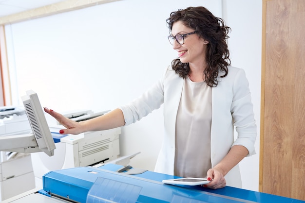 Fröhliche Frau, die Drucker einstellt