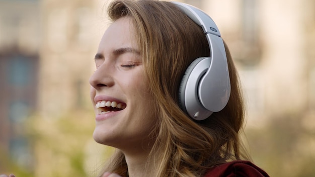 Fröhliche Frau entspannt sich mit Kopfhörern im Freien Hübsches Mädchengesicht, das Musik hört