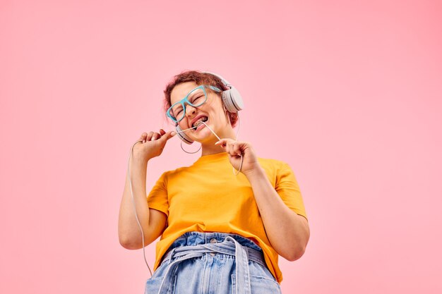 Fröhliche Frau gelbes T-Shirt Kopfhörer Unterhaltung Musik Spaß beschnittene Ansicht unverändert