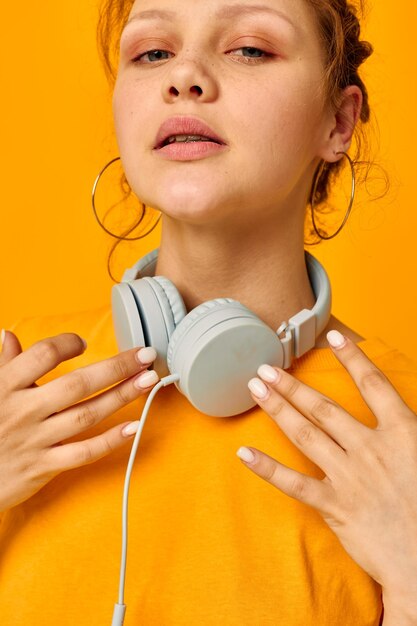 Fröhliche Frau Grimasse Kopfhörer Musiktechnik gelben Hintergrund unverändert