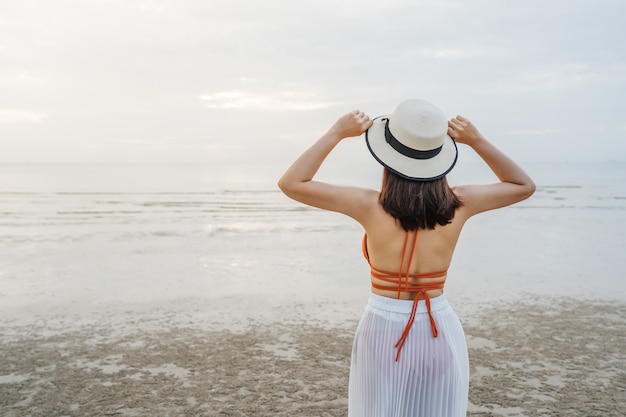 Fröhliche Frau im Bikini, die am Meeresstrand steht