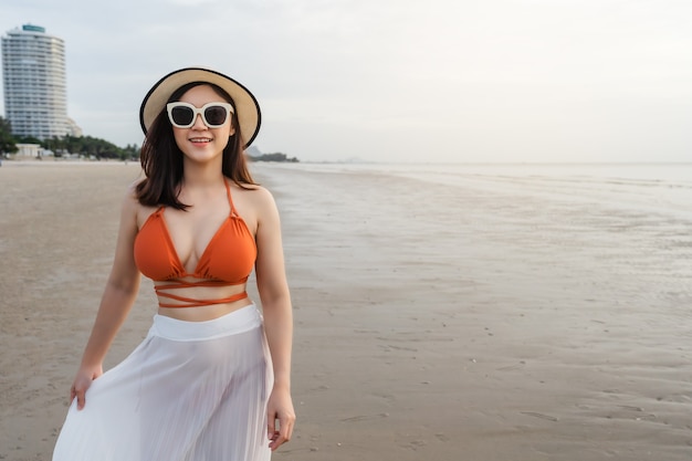 Fröhliche Frau im Bikini, die auf dem Meeresstrand geht