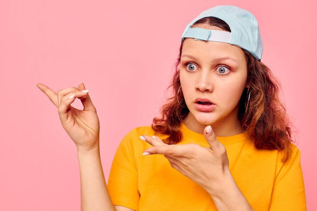 Fröhliche Frau in einem gelben T-Shirt und einer blauen Kappe, die Emotionen aufwirft, beschnittene Ansicht unverändert