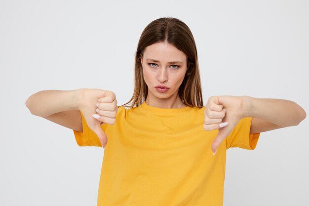 Fröhliche Frau in einem gelben T-Shirt und Jeansshorts im Jugendstil auf hellem Hintergrund