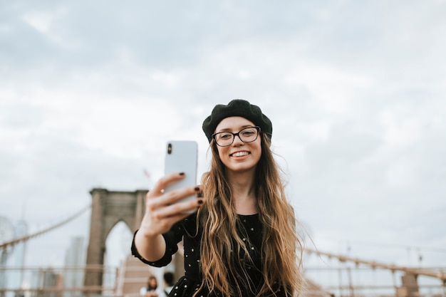 Fröhliche Frau macht ein Selfie mit der Brooklyn Bridge, USA