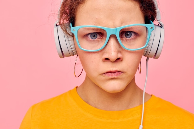 Fröhliche Frau mit blauer Brille, die Musik über Kopfhörer hört, isolierte Hintergründe unverändert