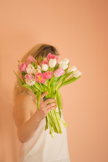 Fröhliche Frau mit Blumenstrauß auf beigem Hintergrund