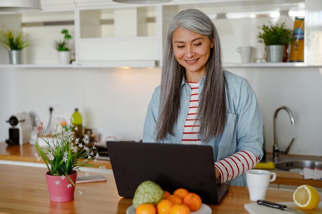 Fröhliche Frau mit tragbarem Laptop in der Küche