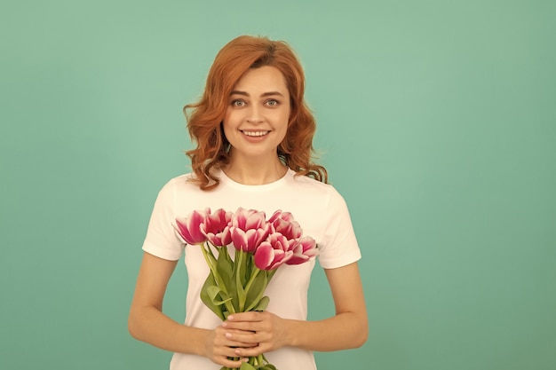 Fröhliche Frau mit Tulpenblumenstrauß auf blauem Hintergrund