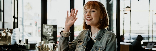 Fröhliche frau winkt im café mit der hand